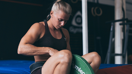 Malin Malle preparing to do pull ups with weight plates added on a dip belt